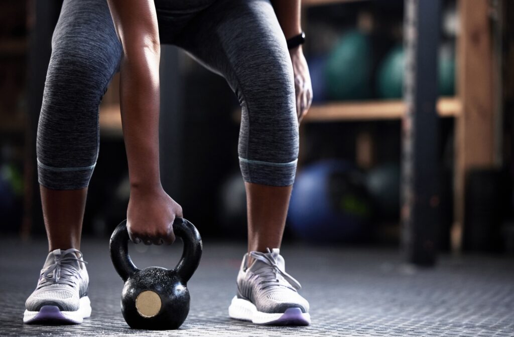A person holding a kettle bell between their feet while lifting weights during a session at the gym.